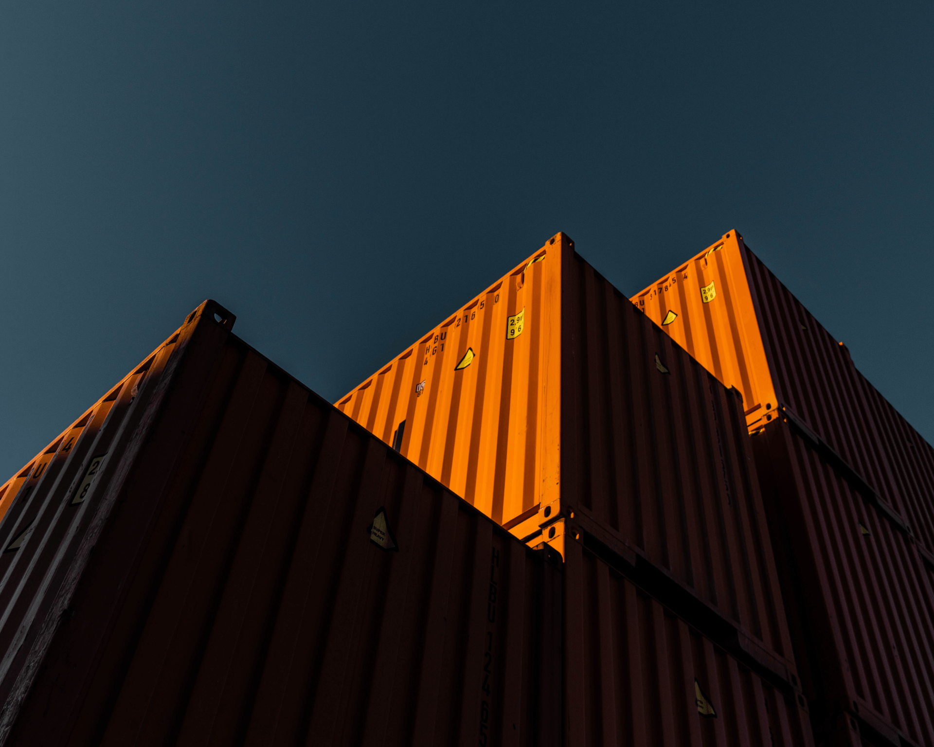 Orange containers seen from below with a dark blue sky as a background